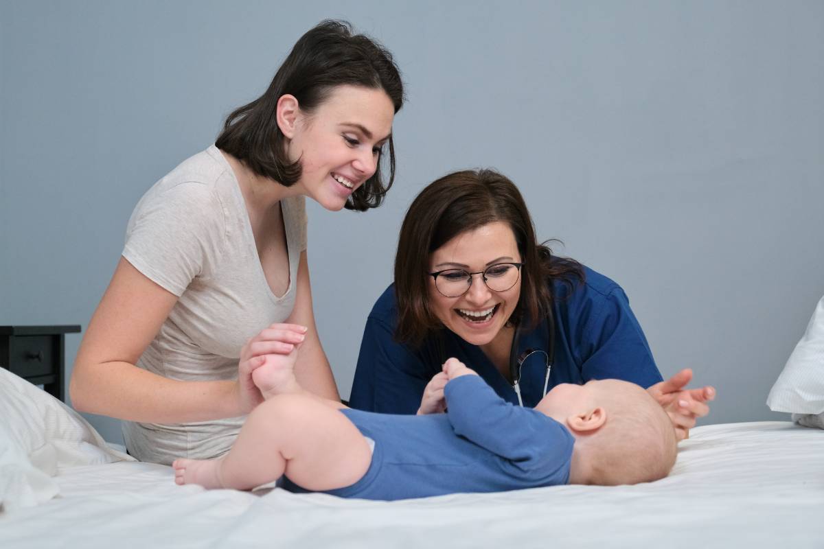 A certified lactation nurse smiles at a baby during an appointment.
