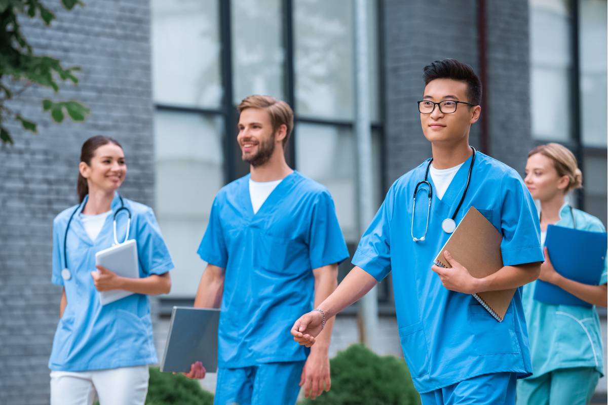 A group of nursing students walk together and discuss colleges with good nursing programs.