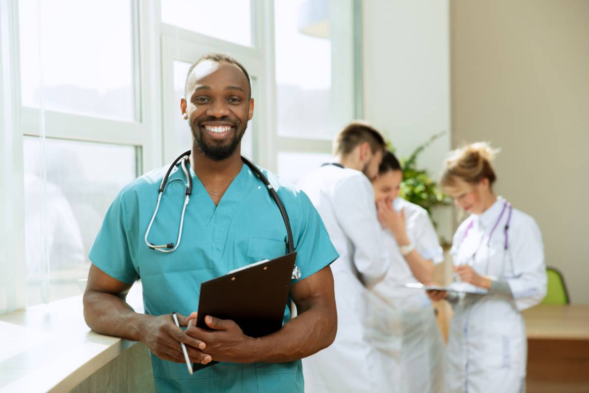 A nurse in teal scrubs enjoys the benefits of working for the VA as a nurse.