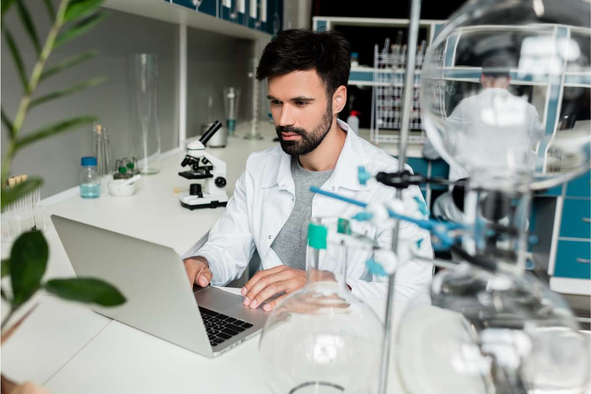 Clinical research coordinator working on his resume on a laptop in a lab.