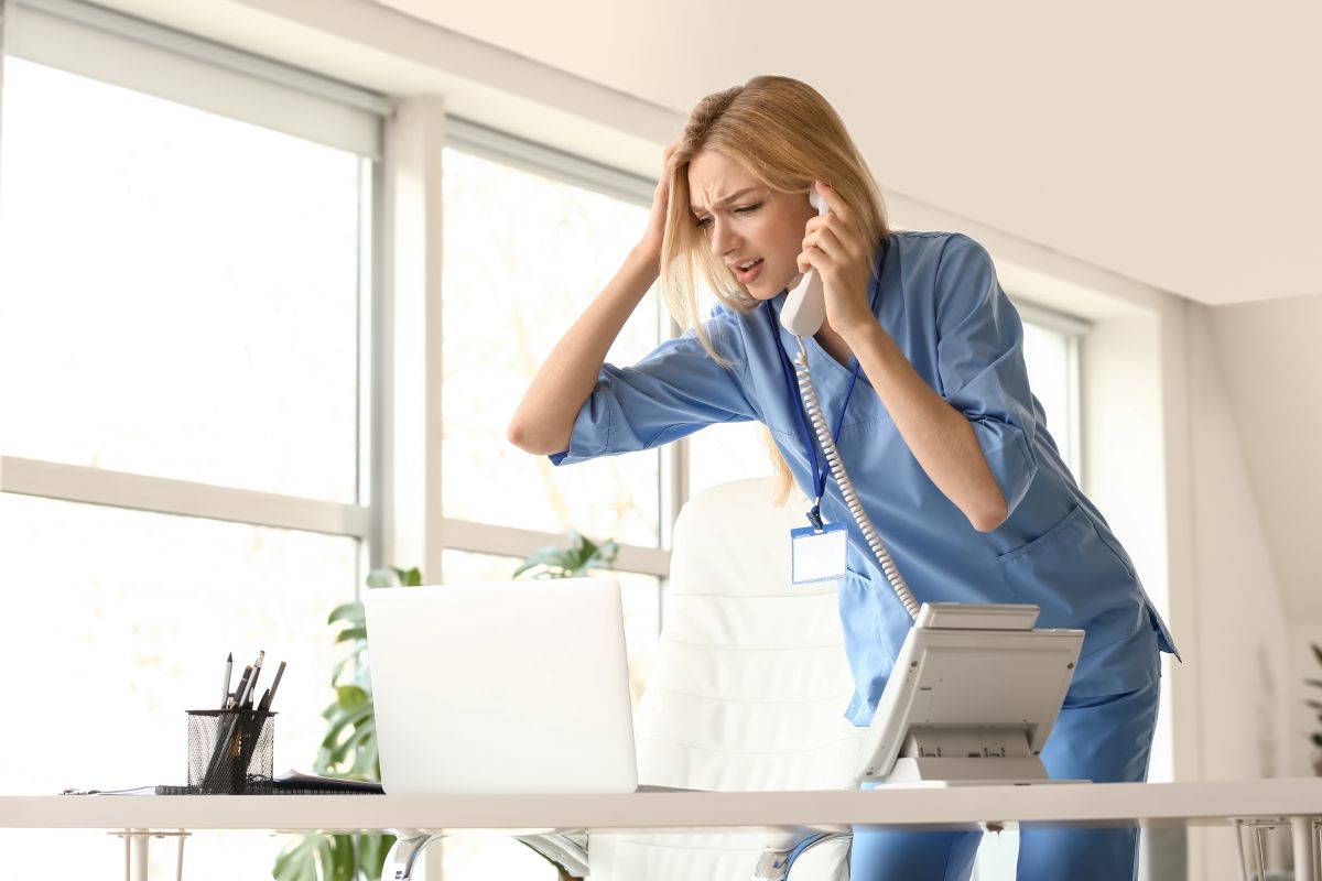 A nurse on the telephone, looking angry, in need of some conflict resolution.