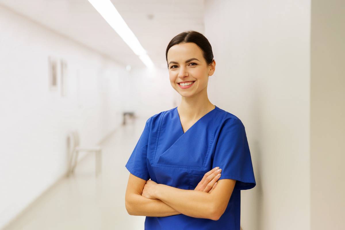 A correctional nurse stands and smiles.