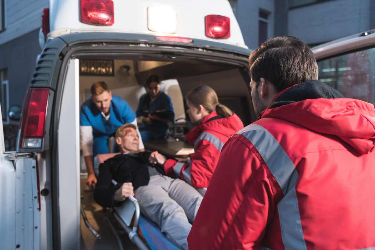 First responders helping injured man into an ambulance.