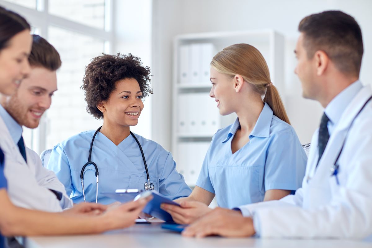 A group of nurses and physicians, talking and smiling.
