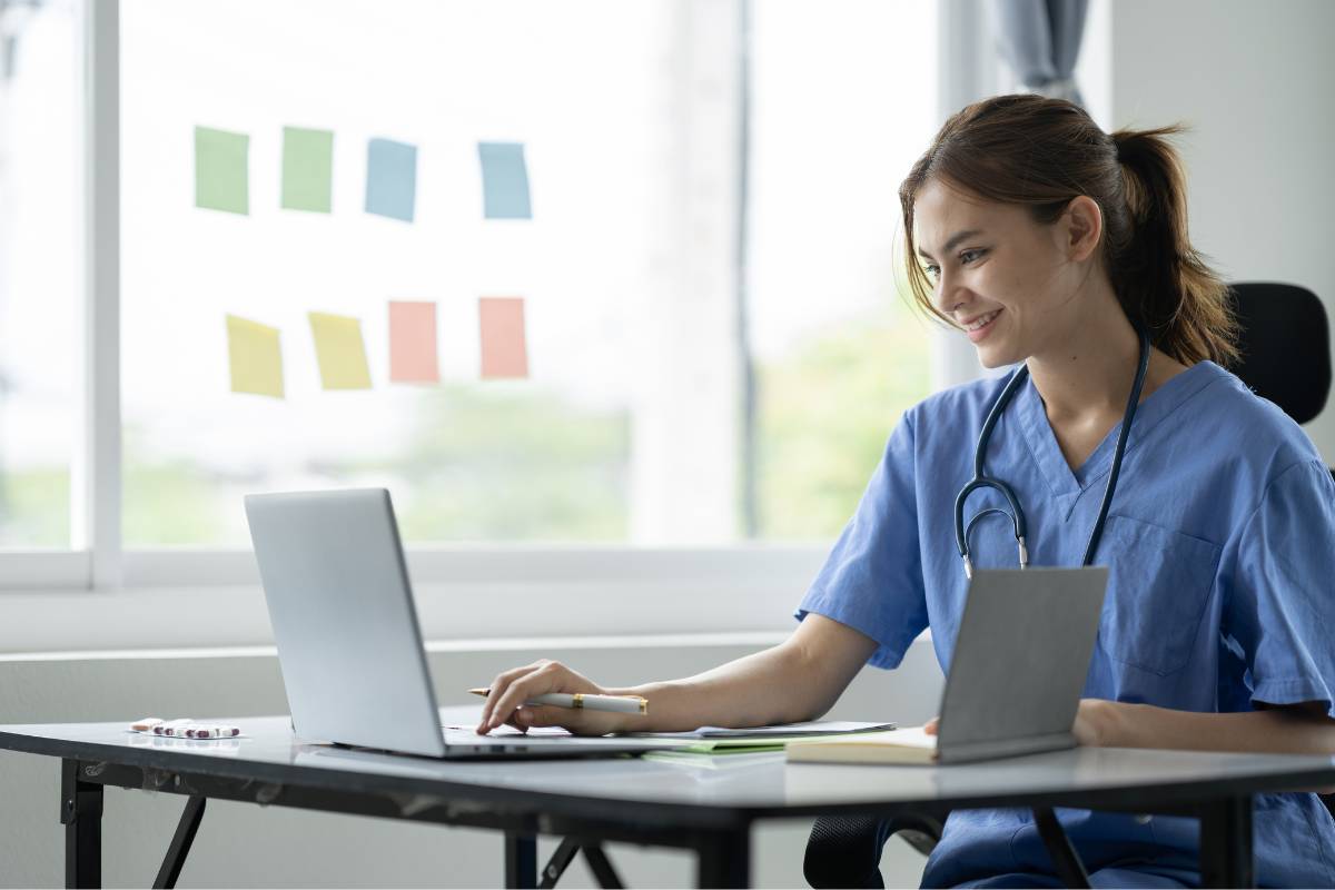 A nurse in blue scrubs writes her hospice nurse resume.