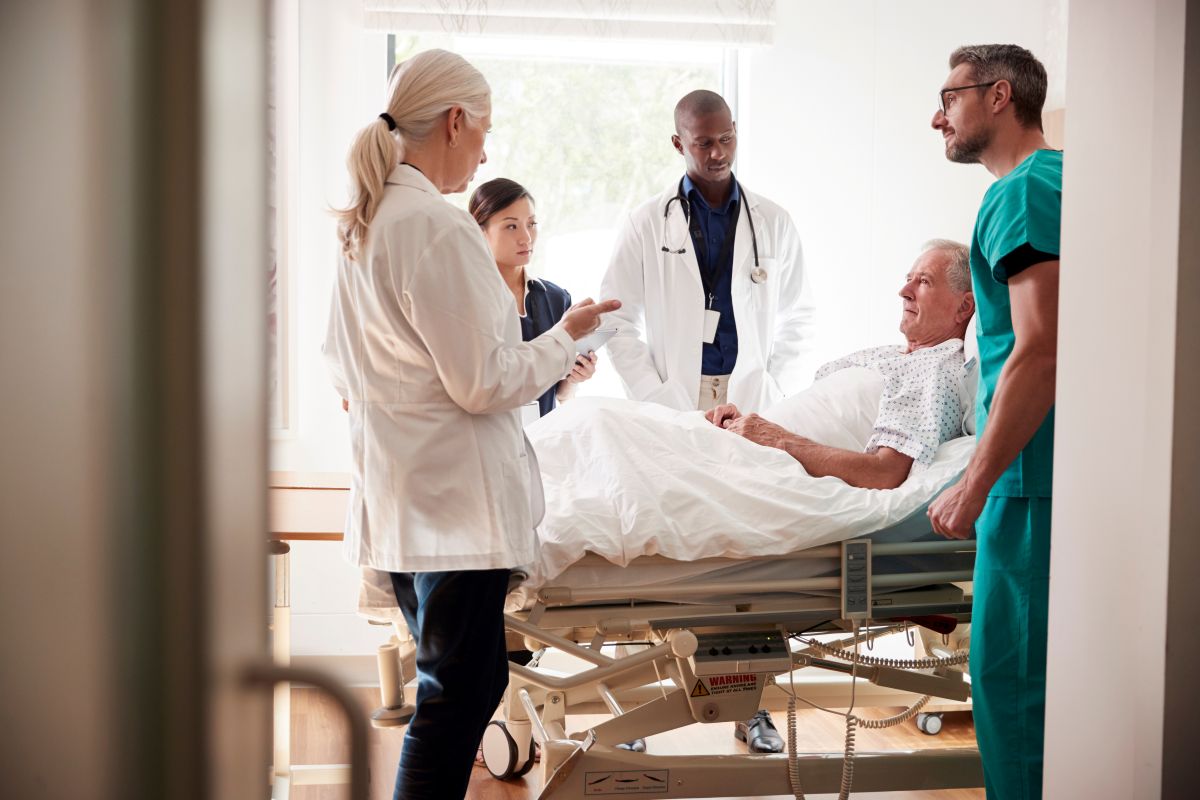 A team of doctors, nurses, and support staff perform interdisciplinary rounds.