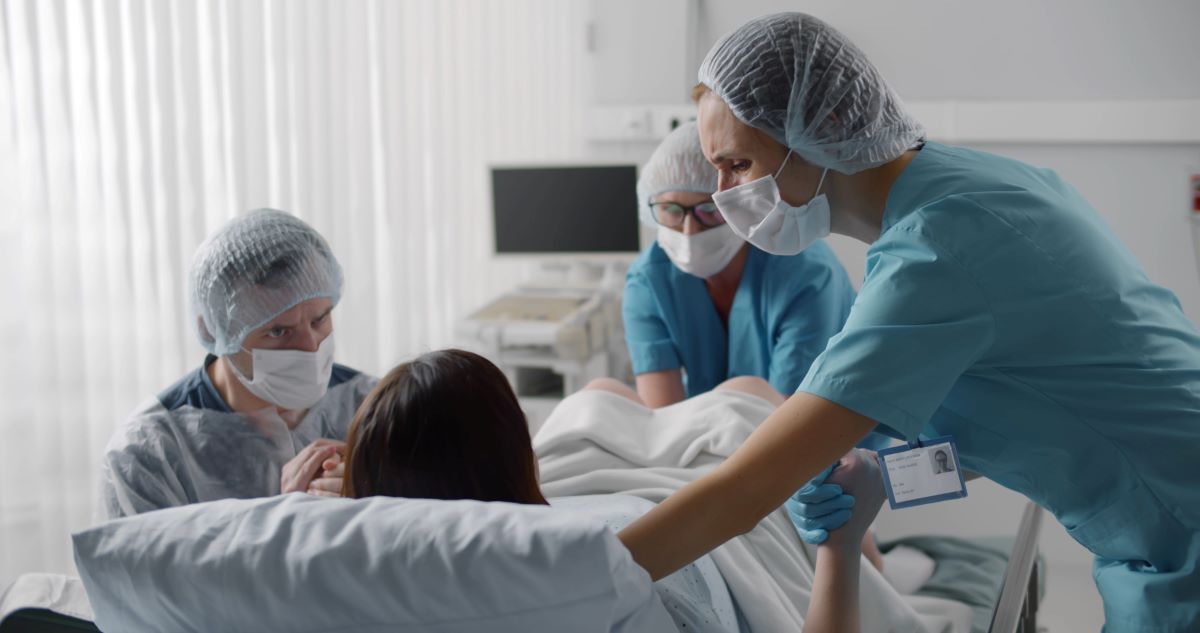 A labor and delivery nurse assists other staff with a delivery.