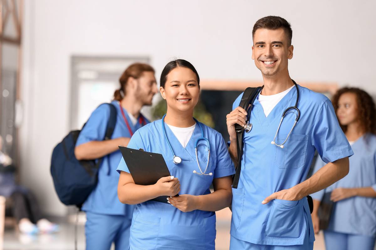 Two nurses stand in a hallway discussing the differences between MSN vs. DNP degrees.