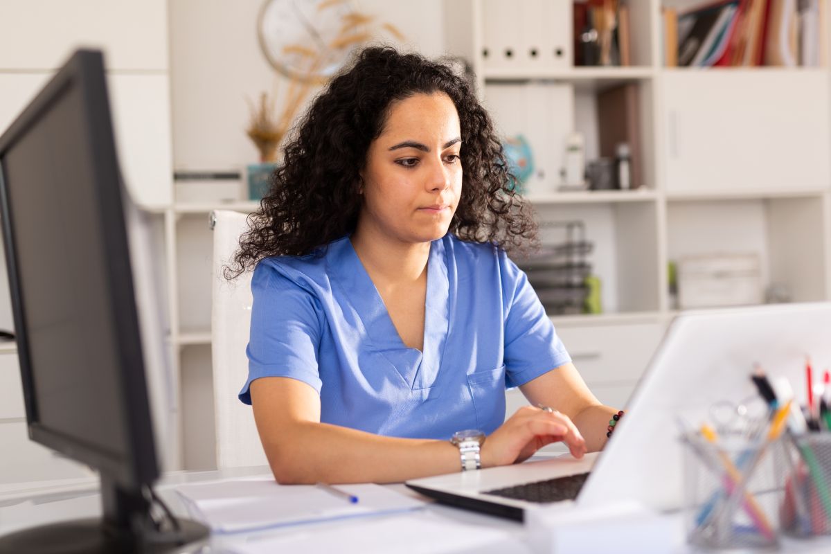 A nurse sits at a computer, demonstrating her facility's use of NDNQI.