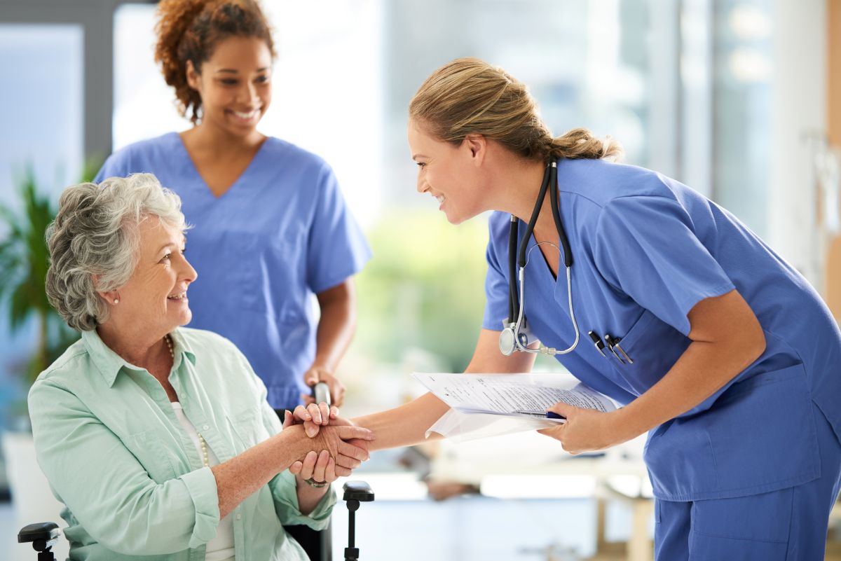 Nurses demonstrating one of many nursing care delivery models as they assist a patient.