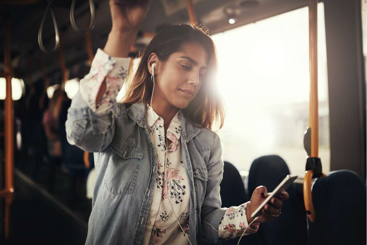 Young woman on a bus and listening to nursing podcasts.