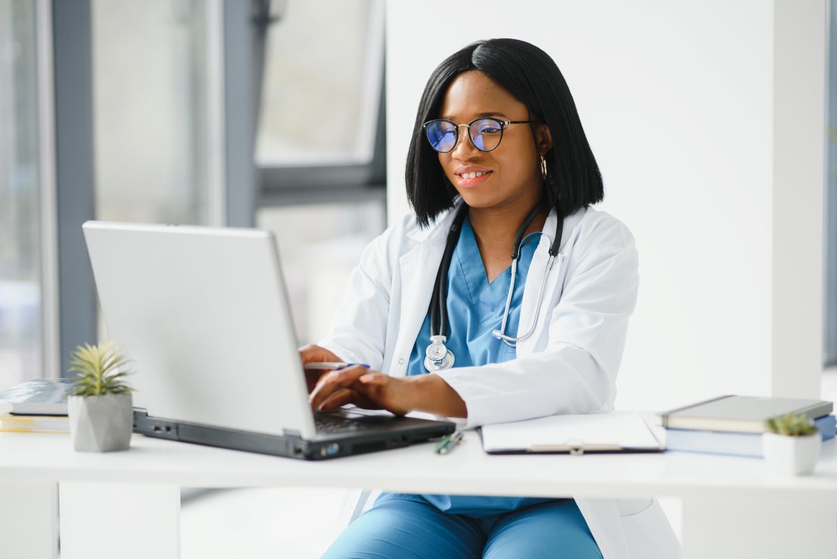 A nurse types something into a laptop computer.