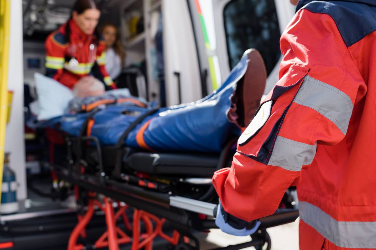 Healthcare professionals with TPATC training wheel a patient into an ambulance.