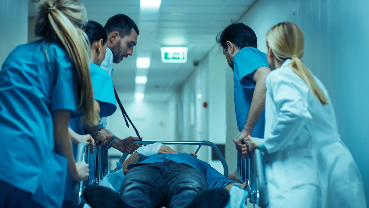 A doctor and attending trauma nurses rush a patient to a hospital room.