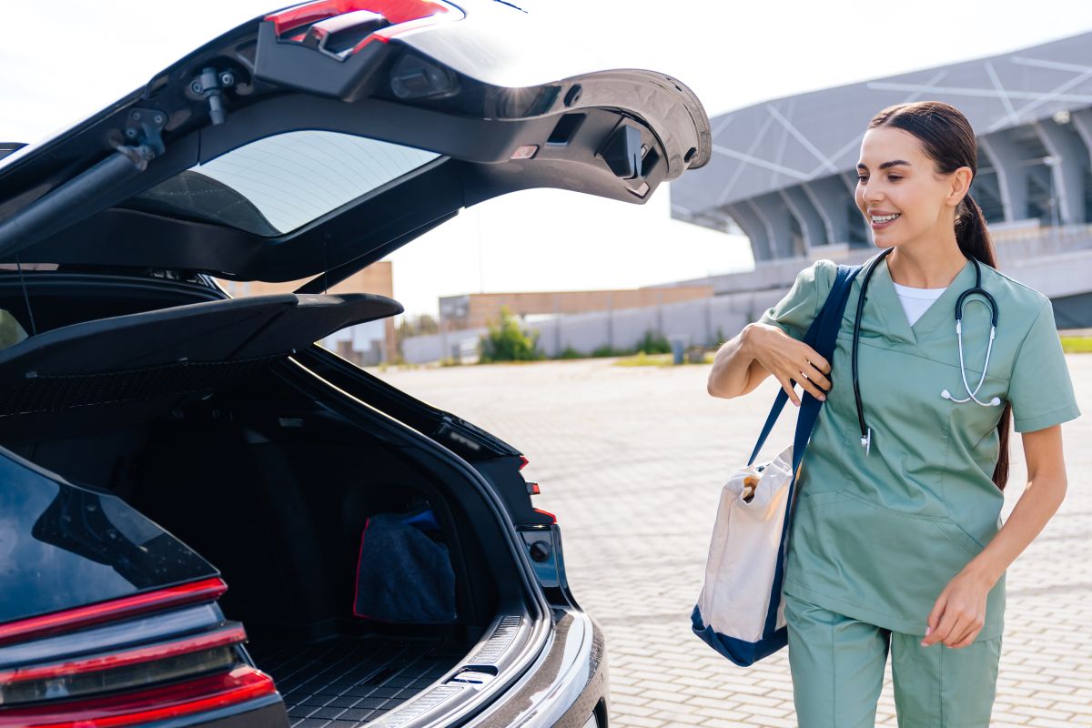 Female nurse packing bag into her car.