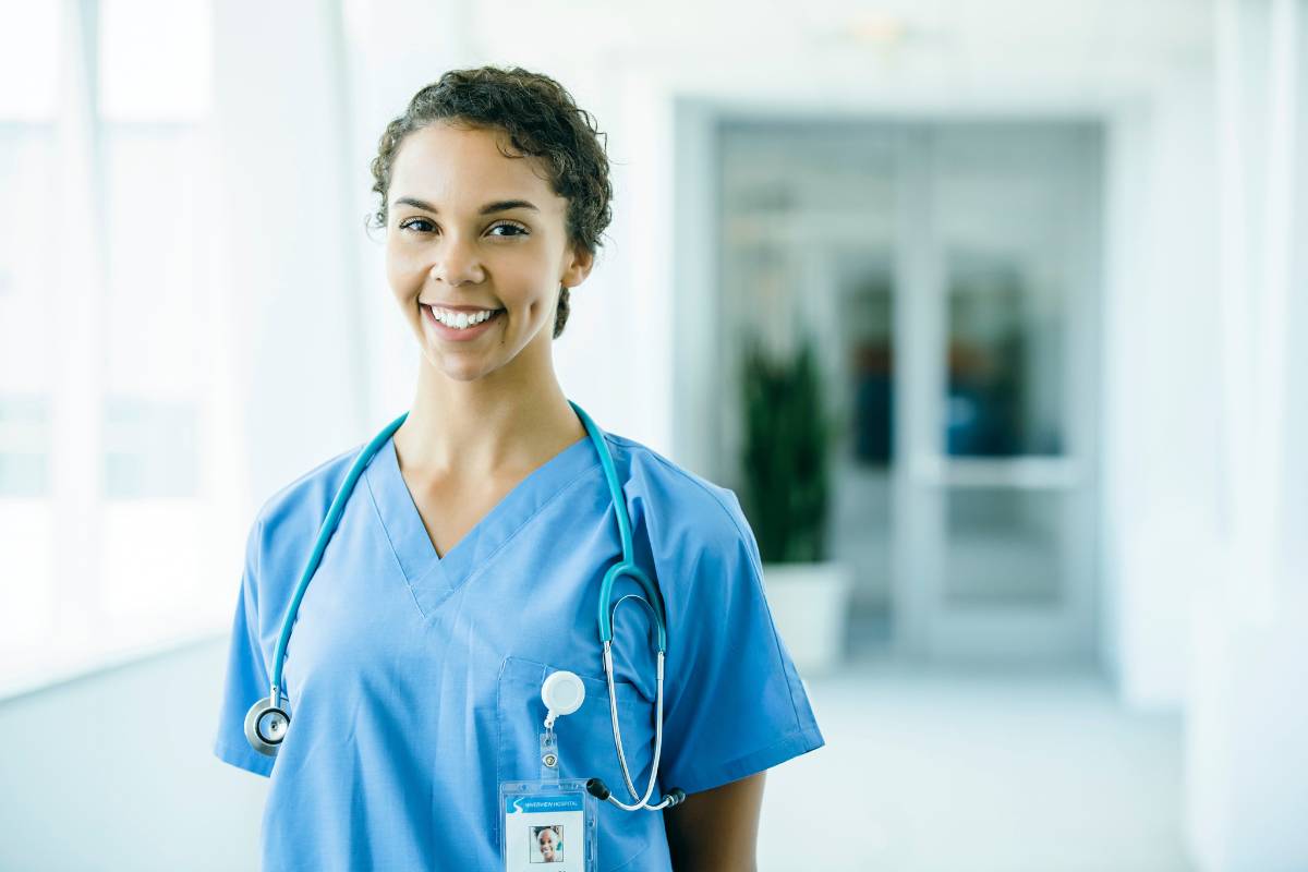 A nursing professional poses for a photo while answering the question, What is an APRN?